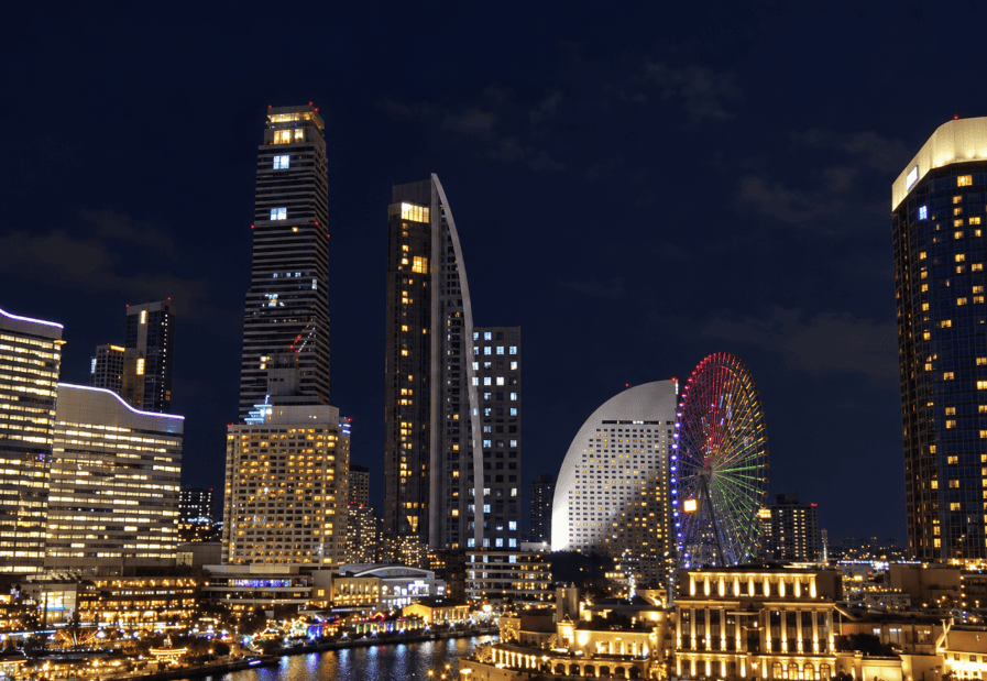 夜空の下でライトアップされた観覧車と高層ビルが並ぶ水辺の夜景