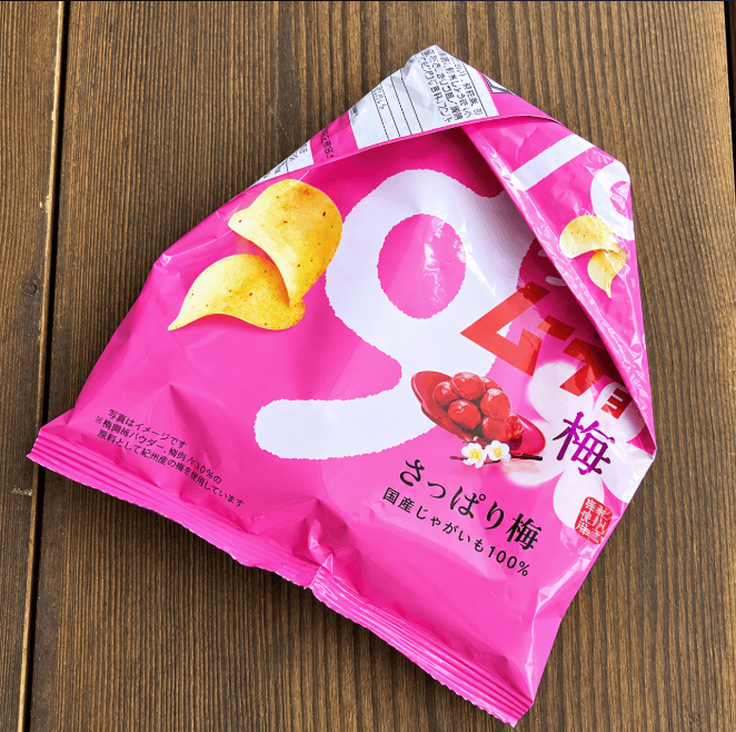 袋の口を折りたたんで閉じ、木製の台に置いたピンク色のお菓子袋