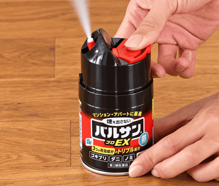 床に置いた霧タイプのバルサンの操作部を押し、白い霧が噴出している様子